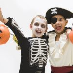 7 Halloween Marketing Ideas That Drive Sale Boys in skeleton and pirate costumes holding jack o'lantern