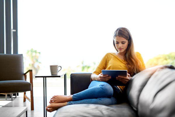 woman in yellow top on couch looking at ipad