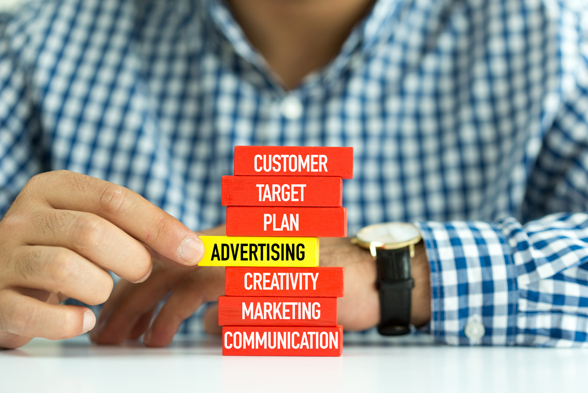 Choosing A Type of Ad Agency Businessman Building ADVERTISING Concept with Wooden Blocks