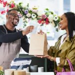 Small business owner handing a customer a bag with a handwritten thank-you note