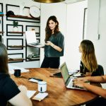 Female graphic designer presenting project ideas to colleagues during meeting